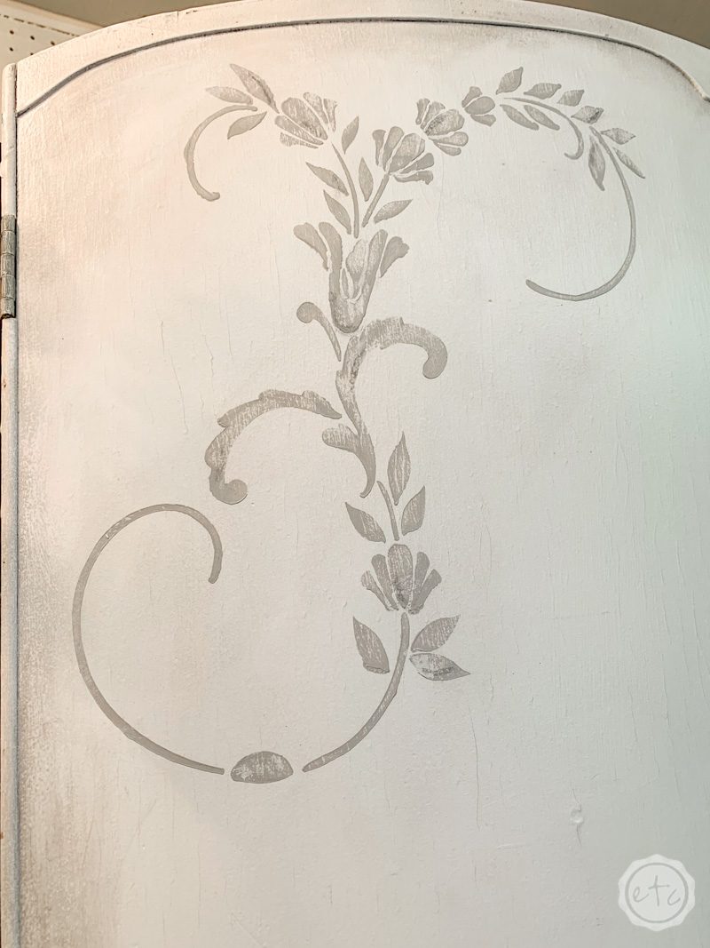 Stencil detail in gray on a white crackled armoire. 