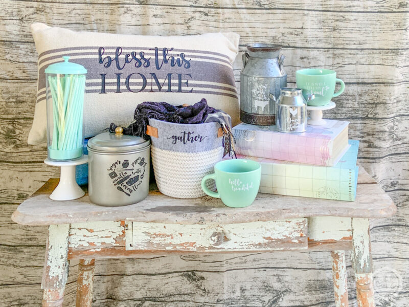 A farmhouse inspired group of home decor items: pillows, baskets, mugs, canisters and milk jugs all with iron on vinyl decals. 