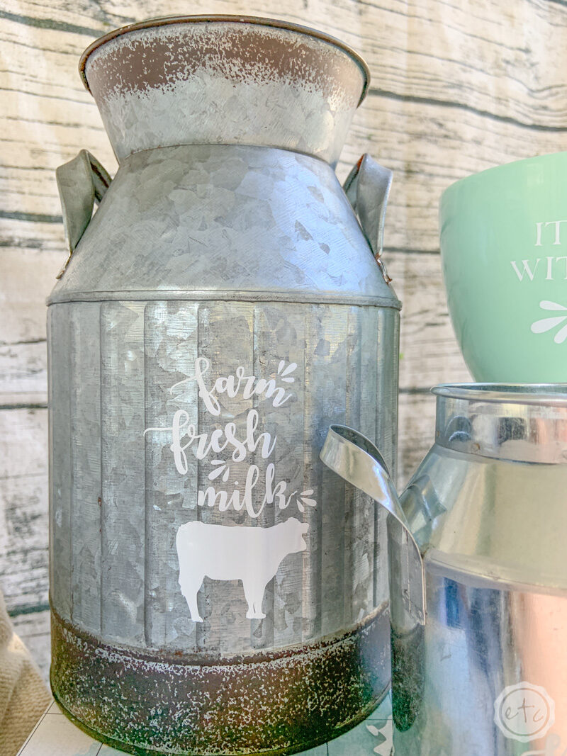 A metal milk can with a fun iron on design that reads "farm fresh milk" with a cute little icon of a cow