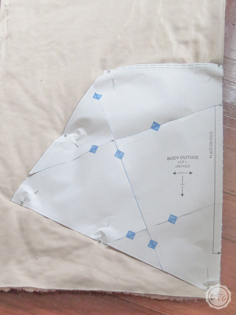 Showing how to pin a large pattern piece on the fold of the fabric.