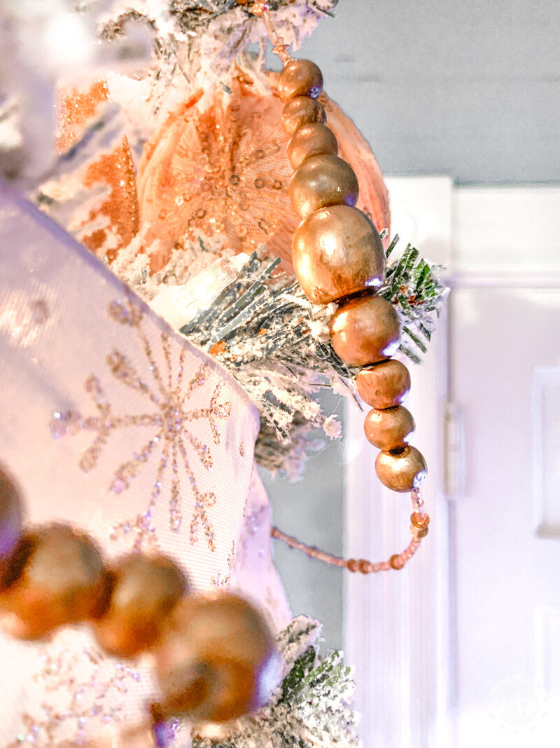 rose gold wood bead garland at the top of a Christmas tree