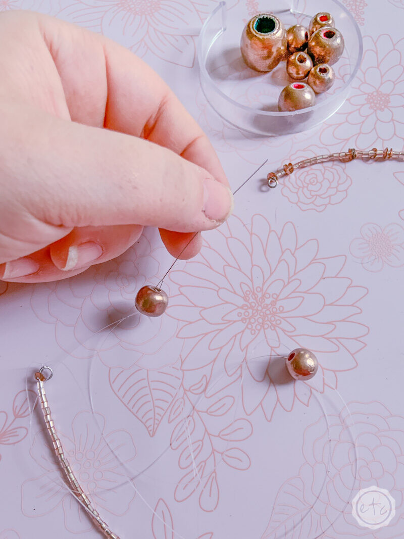 Stringing beads onto clear cording to form bead garland